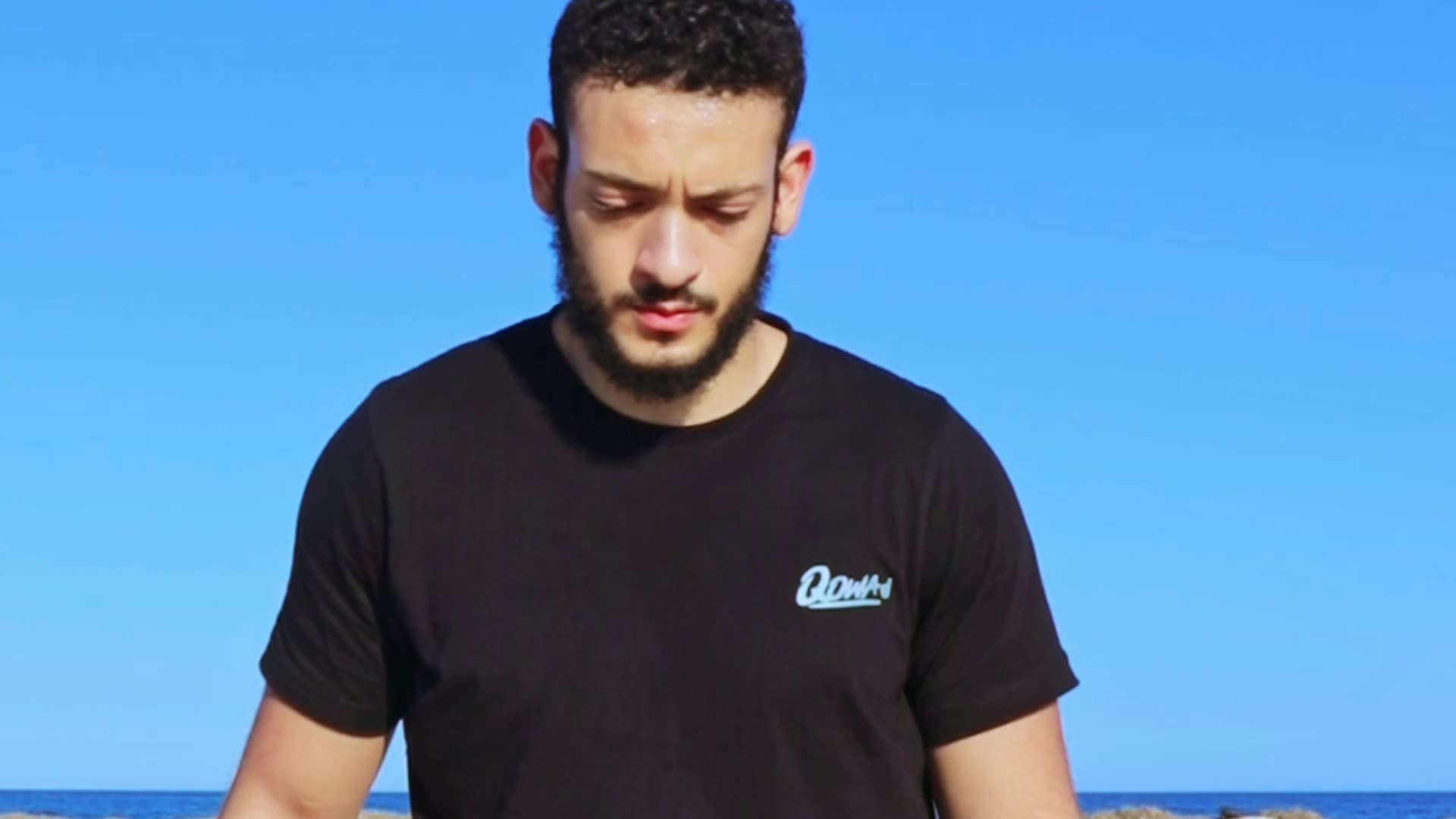 Homme portant le t-shirt Qowa au bord de la mer